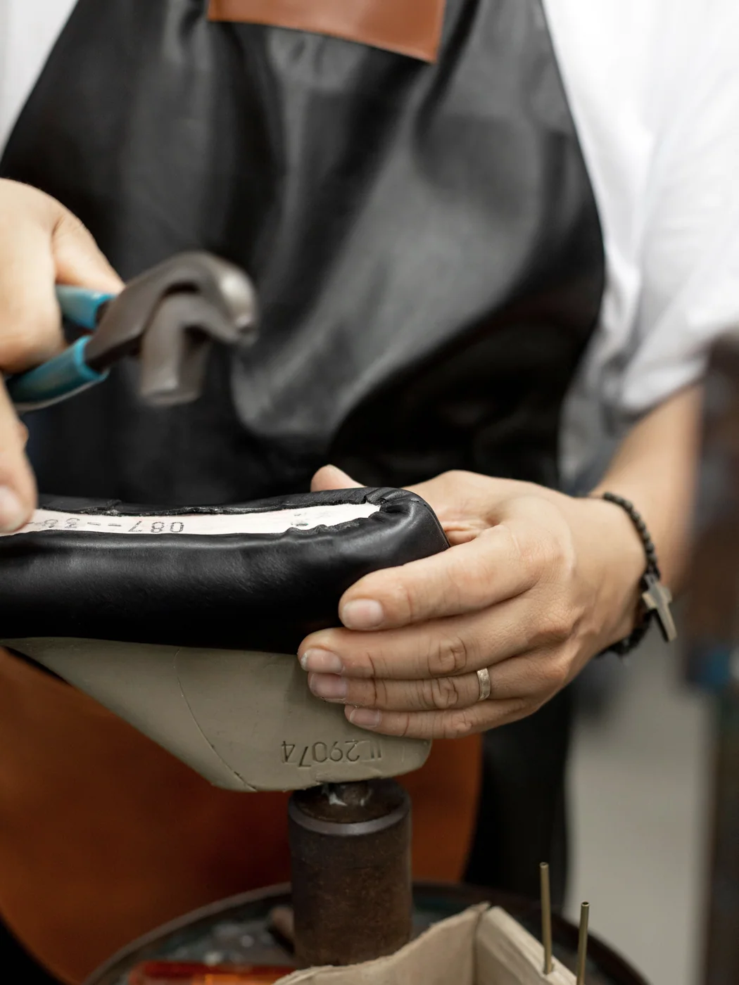 Cordonnier travaillant un soulier sur une forme en atelier
